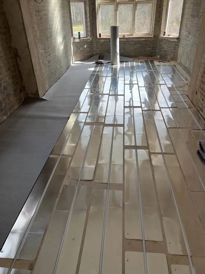 Gulvvarme med aluminiumsplader i stue med vinduer